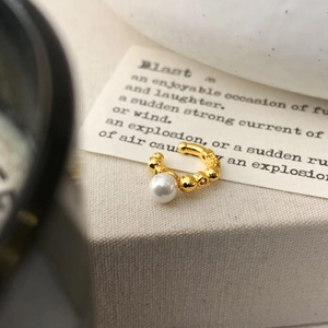 Detail view of a gold-plated pearl ear cuff on a decorative display stand