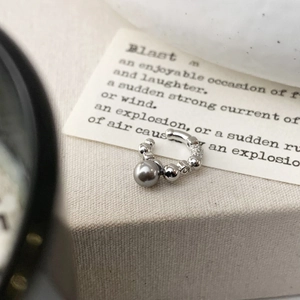 Macro shot of a silver-toned ear cuff with a grey pearl and shimmering diamond accents
