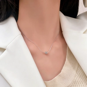 Elegant silver necklace with sparkling pavé ball pendant worn on a white suit model