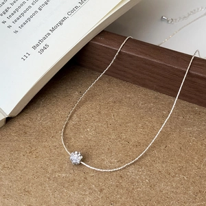 Detailed close-up of a silver snake chain necklace featuring a crystal pavé ball pendant