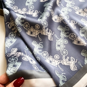 Detailed view of horse carriage print scarf with smooth silk texture and striped border
