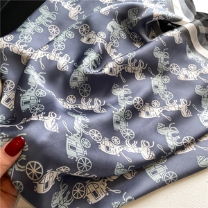 Detail of silk satin scarf featuring elegant horse carriage prints and striped borders