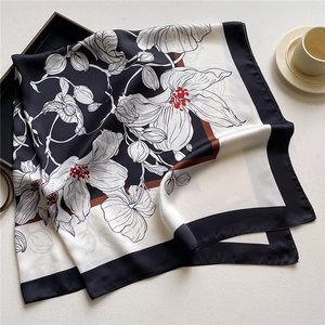 Detail of silk scarf with white floral print and red accents on a tray background
