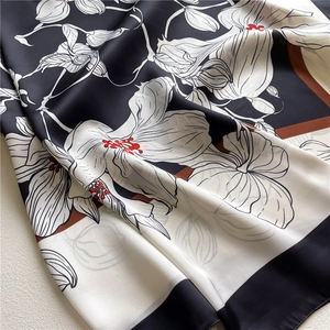 Detailed view of silk satin scarf featuring large floral prints and soft fabric texture