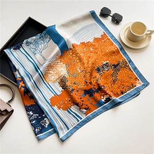 Detailed view of large printed satin scarf featuring artistic landscape and glossy finish