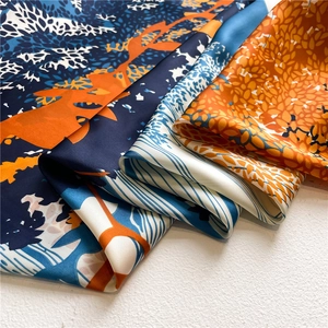 Close-up of silk-textured navy and orange scarf with abstract nature print layers
