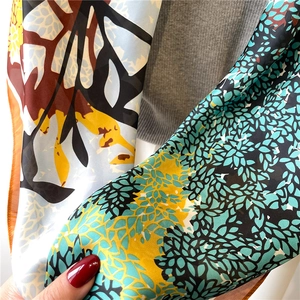 Detail shot of the 110cm silk-like scarf featuring green and yellow leaf patterns