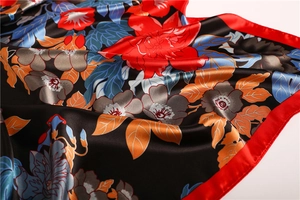 Detail of satin floral scarf showing smooth silk texture and red peony flower patterns