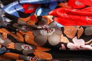Macro shot of elegant floral satin fabric with vibrant red and blue patterns on black