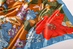 Detail of luxury floral satin scarf with elegant golden bronze tones and vivid flower print