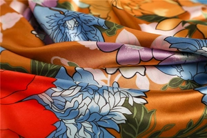 Macro detail showing glossy floral satin fabric texture with vibrant hand-painted patterns