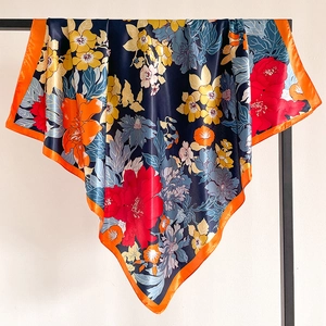 Detailed view of large floral navy blue silk scarf with bright orange satin hem edges