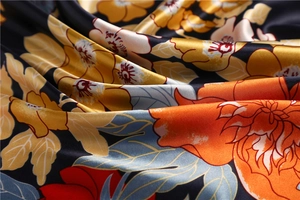 Close-up of elegant floral pattern on luxurious satin silk scarf with vibrant gold flowers