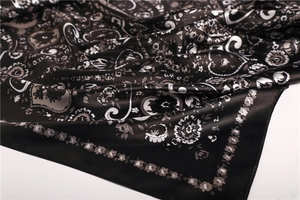 Detail of elegant black and white floral paisley satin scarf with glossy silk texture