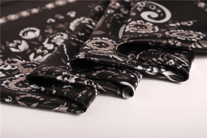 Close-up of black satin scarf with white floral and paisley patterns and silky texture
