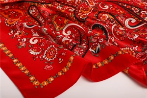 Detailed close-up of red satin scarf showing intricate paisley and floral vine patterns