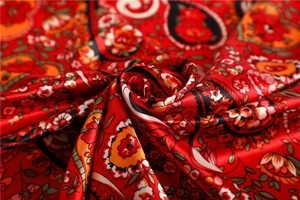 Detail of red floral paisley silk scarf with glossy texture and intricate pattern