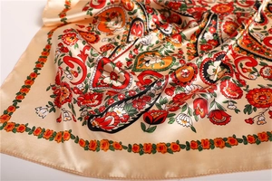 Detailed macro view of champagne gold satin silk scarf with vivid paisley and floral print