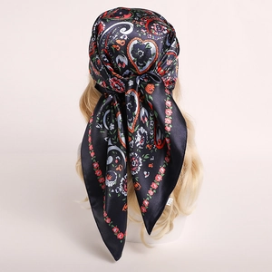 Close-up of black satin headscarf with floral paisley patterns tied on a mannequin