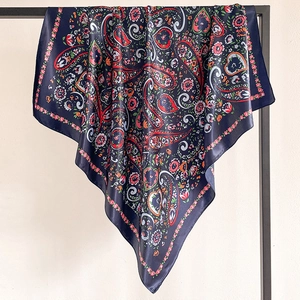 Close-up of a navy blue silk scarf with red paisley patterns hanging on a black hanger