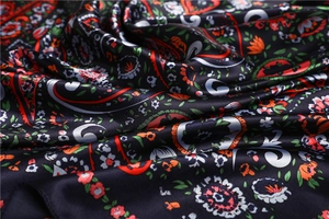 Close-up of silky satin scarf with vibrant paisley and floral patterns on black fabric