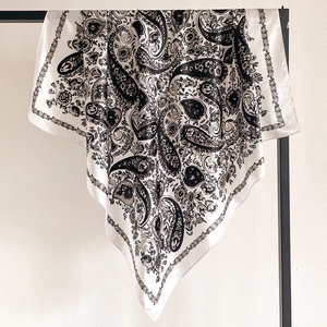 Detail of satin square scarf featuring black and white paisley patterns and floral borders