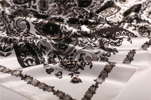 Macro detail of elegant black and white floral paisley pattern on silky satin fabric scarf
