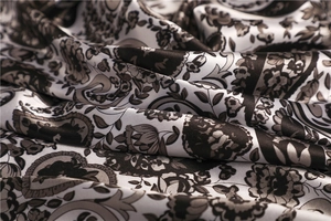 Detailed macro shot of vintage paisley pattern on soft brown and white satin silk scarf