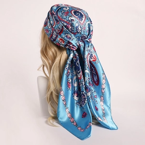 Detail of blue paisley floral satin scarf styled as a headwrap on a mannequin