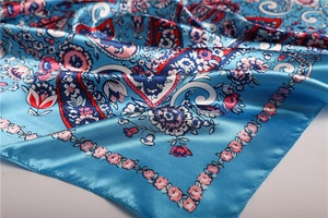 Detail of blue satin silk scarf with red floral paisley pattern and shiny finish