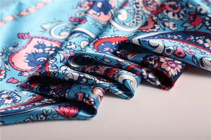 Detail of silk scarf showing glossy satin fabric with colorful floral paisley patterns