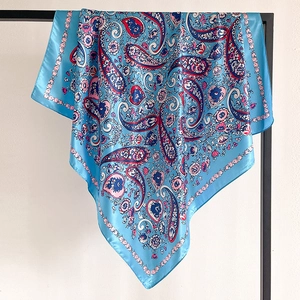 Detail of light blue paisley satin silk scarf hanging on a metal display stand