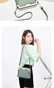 Close-up of floral embroidery and adjustable strap on a green shell-shaped shoulder bag