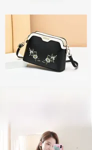 Detail of black and white shell bag with daisy embroidery and gold hardware accents