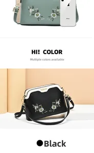 Compact black crossbody shell bag with daisy embroidery compared to iPhone size