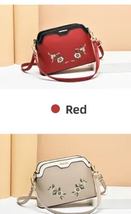 Detail of red shell-shaped crossbody bag with exquisite floral embroidery and metal logo