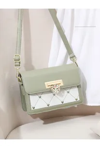 Détail du fermoir cœur vert menthe et broderie losange sur un sac bandoulière élégant