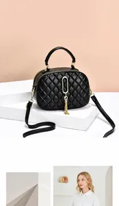 Detail view of black quilted PU leather crossbody bag with gold lock and tassel charm