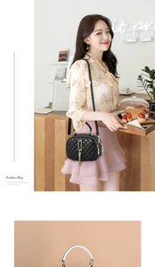 Close-up of black quilted shoulder bag with gold tassel pendant in a cafe setting
