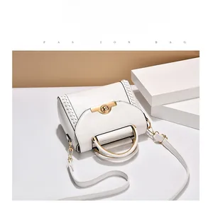 Close-up of white structured handbag with woven edge, gold clasp, and metal ring handle