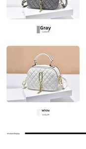 Detailed view of quilted crossbody bag with metal ring and tassel in gray and white