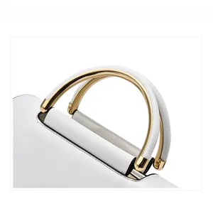 Close-up of elegant white leather handle and semi-circular golden metal grips on handbag