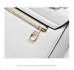 Close-up of smooth gold metal zipper and white textured leather on minimalist handbag