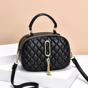 Elegant black quilted diamond crossbody bag with gold chain tassel on a white pedestal