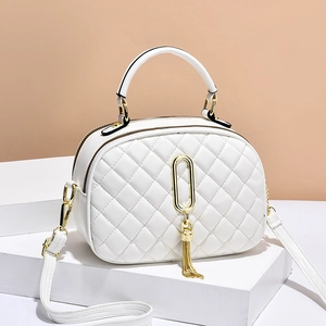 White quilted crossbody bag with gold tassel chain on geometric white display stand