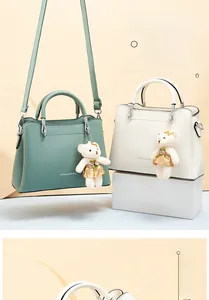 Détail de sacs à main trapèze vert menthe et beige avec pendentif ours et poignée métal