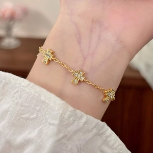 Elegant gold cross bracelet with micro-paved zircons worn on wrist in warm home setting