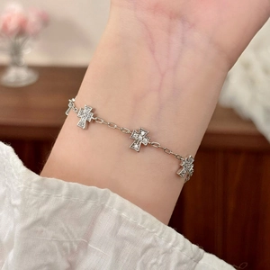 Elegant silver cross bracelet with cubic zirconia micro-pave charms worn on female wrist