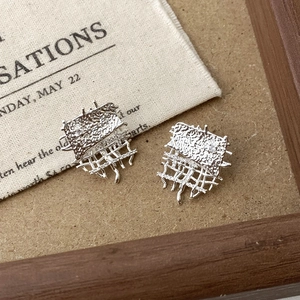 Silver textured geometric earrings with woven mesh and fringe detail on vintage fabric