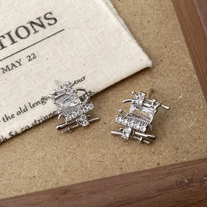 Silver woven stud earrings featuring a rectangular gemstone on rustic linen background